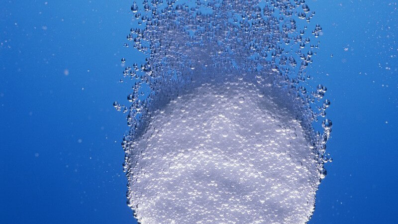 Kopfschmerztablette fällt ins Wasser und sprudelt