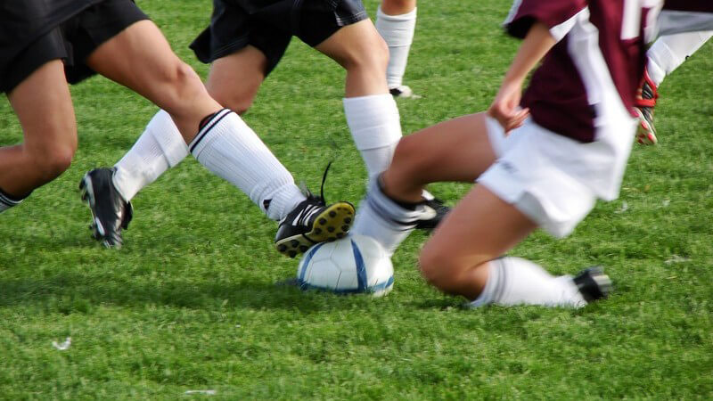 Ausschnitt Frauenbeine beim Fußballspiel auf Rasen