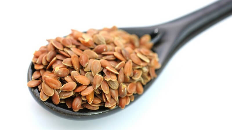Nahaufnahme Leinsamen auf Löffel, weißer Hintergrund