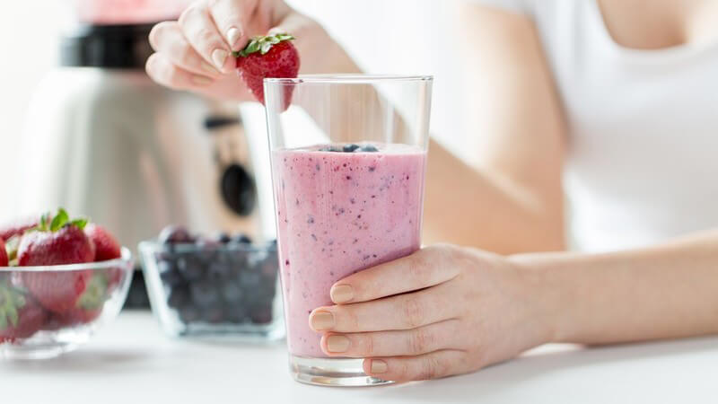 Milchshake aus Blaubeeren und Erdbeeren mit Erdbeere am Glasrand