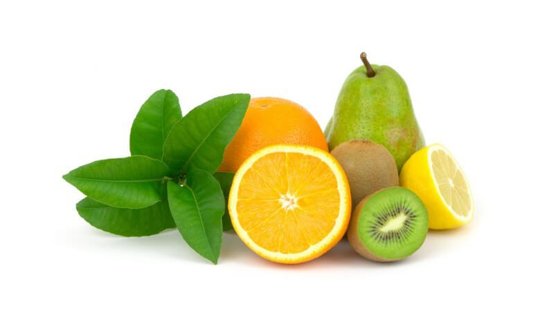 Frische Orangen, Kiwis und eine Birne, teils halbiert auf weißem Hintergrund